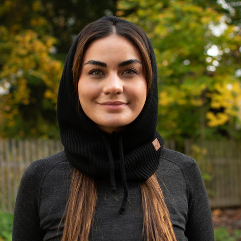 Frau mit einem Merino Oversize Balaclava in der Farbe schwarz in der Natur.